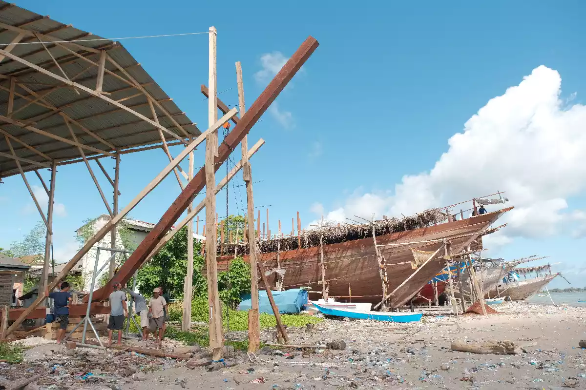 Phinisi hull on the stocks under bamboo scaffolding at an Indonesian shipyard