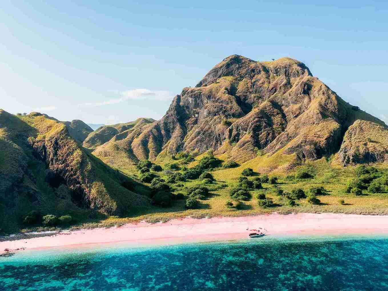 Pink sand below steep green peaks in Komodo National Park