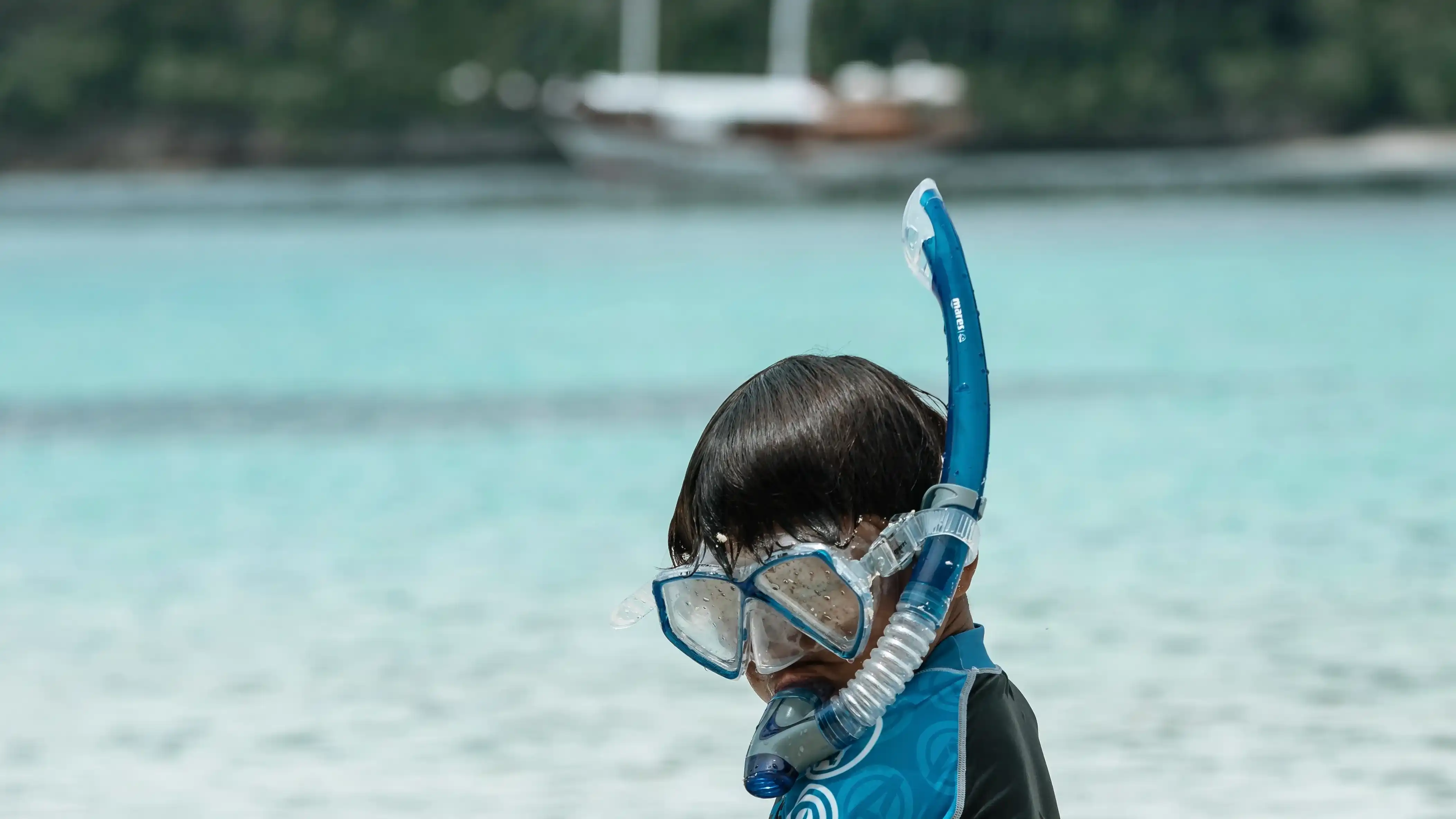 A child in a snorkelling mask in shallow water