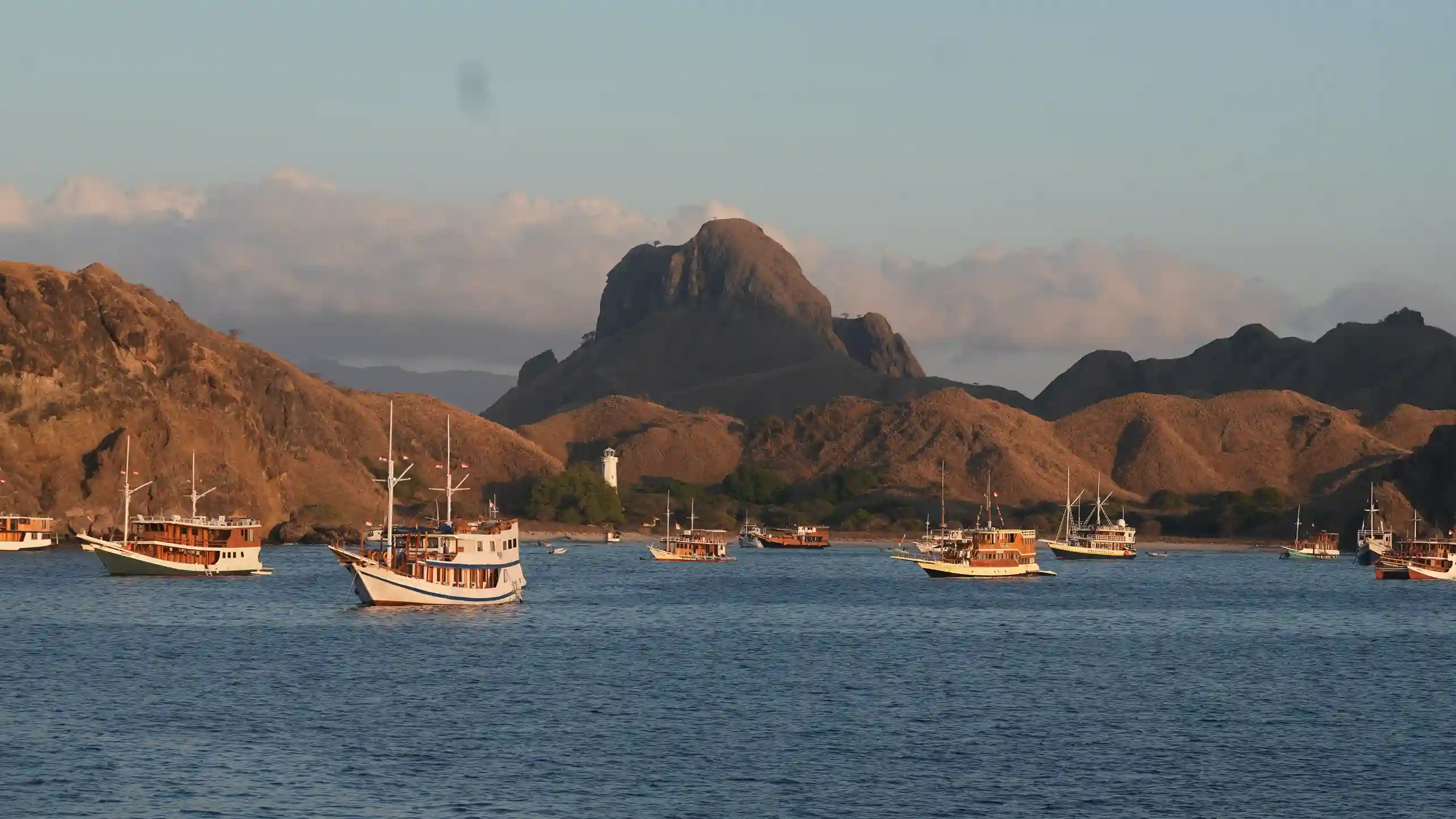 Komodo Open Trip - Luxury Phinisi sailing boat cruising through Komodo National Park with turquoise waters and islands