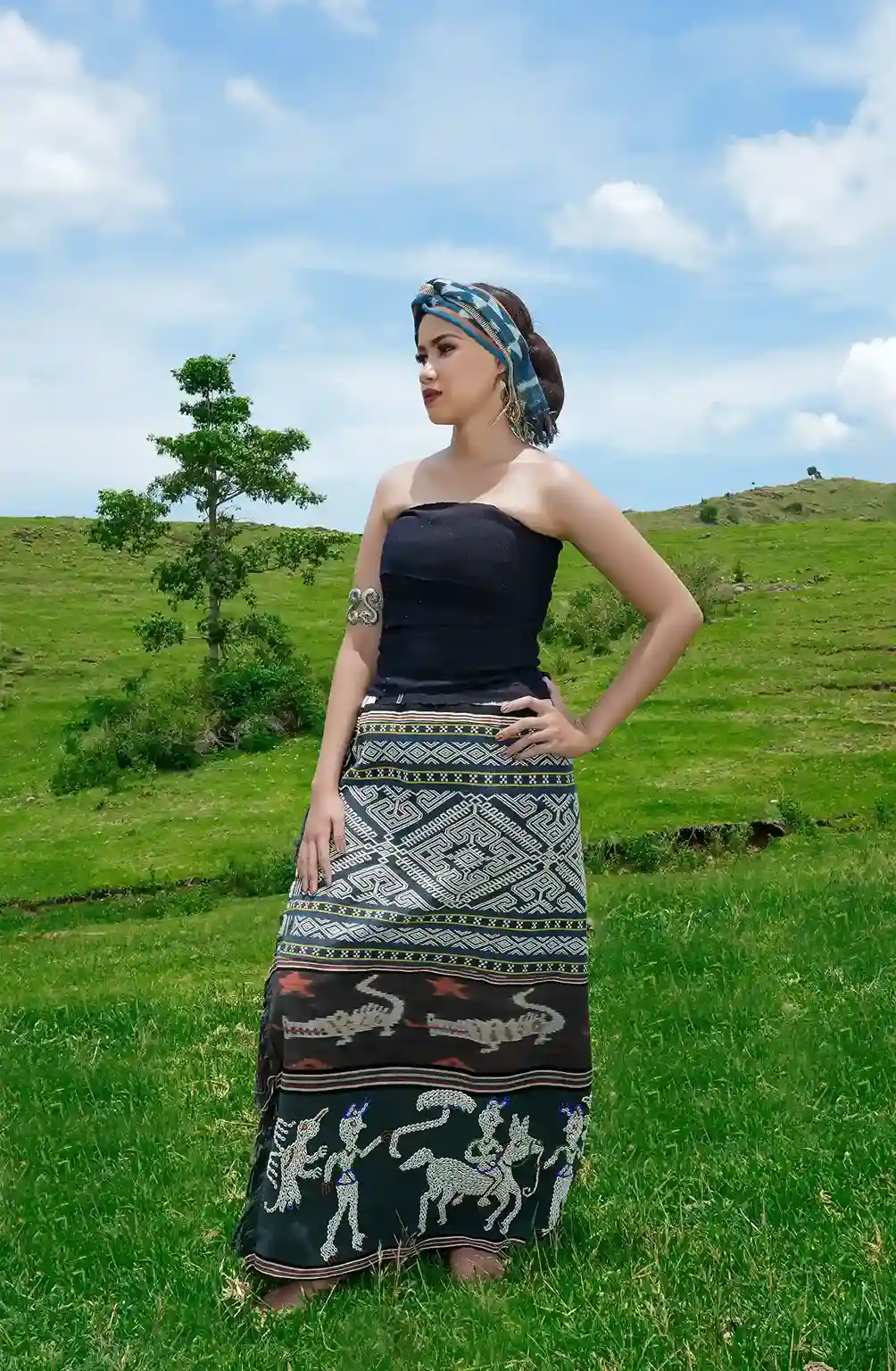 A woman in an ikat wrap looking out over a traditional Sumbanese village