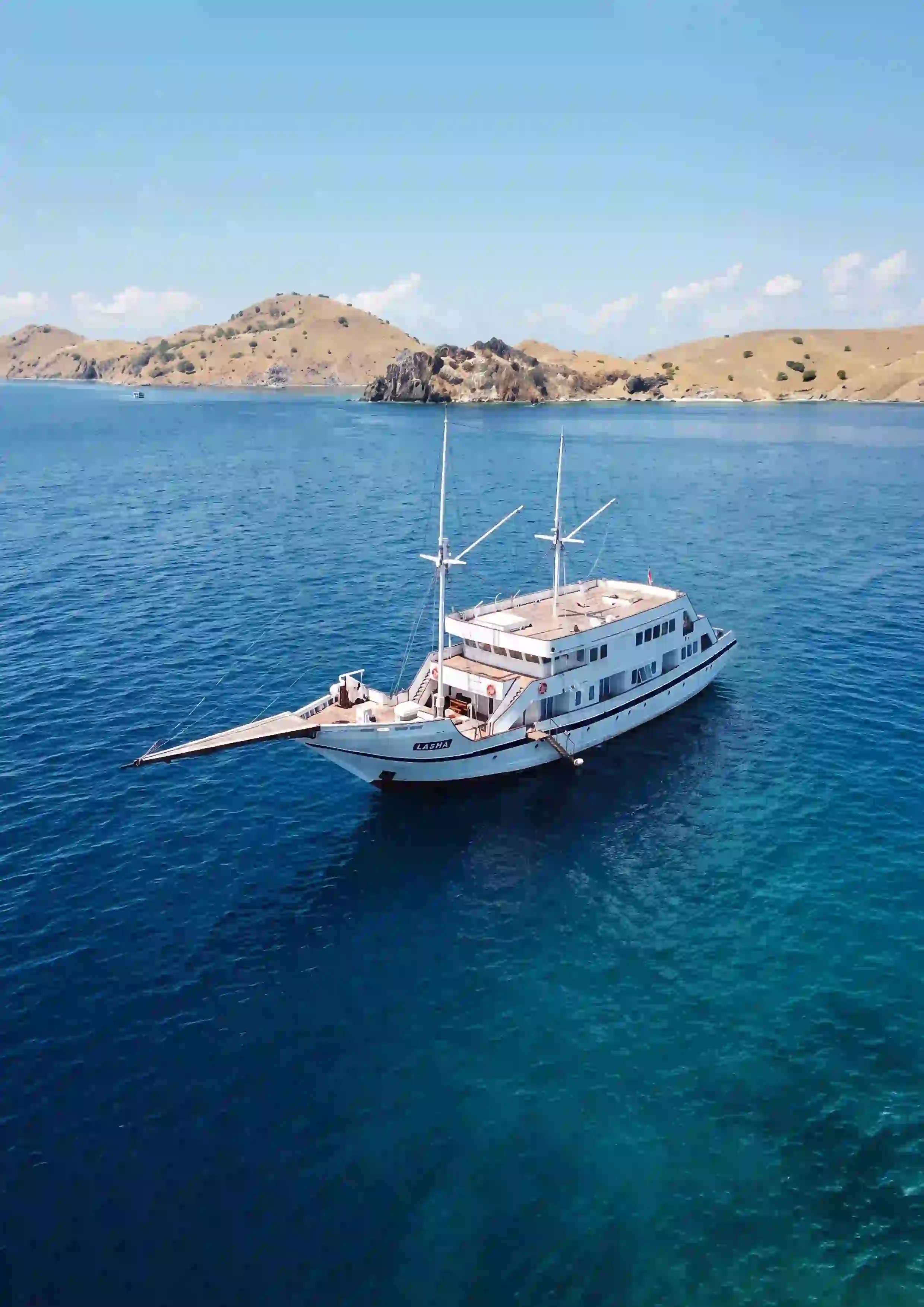 White catamaran boat floating on clear turquoise water.