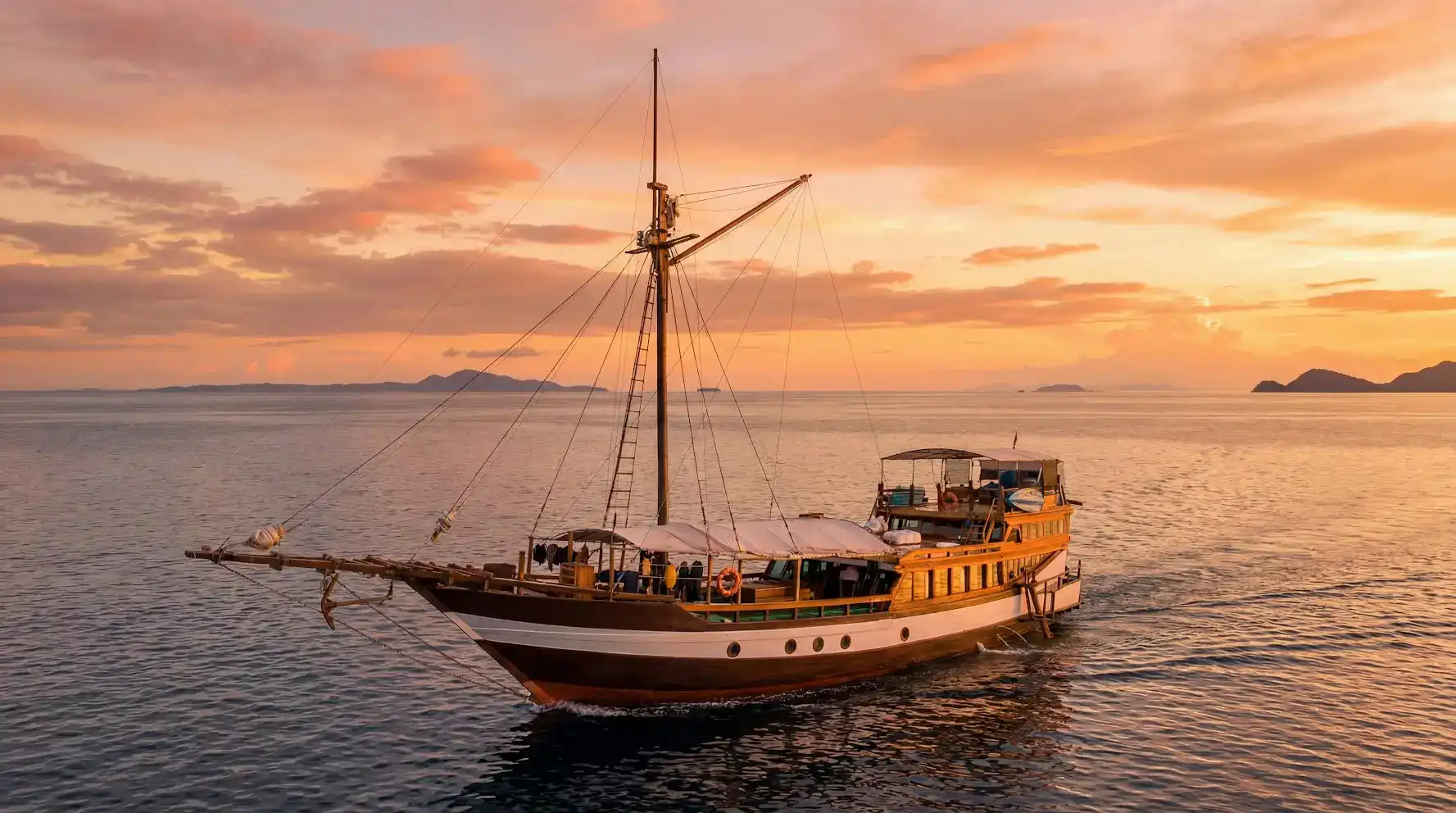 Wellenreng Liveaboard traditional phinisi cruising at sunset in Raja Ampat | Komodo Luxury
